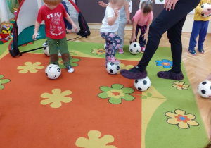 Dzieci naśladują trenera podczas ćwiczenia z piłką