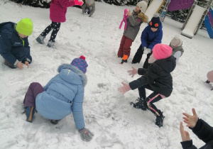 Zimowe zabawy na śniegu, dzieci lepią kule śniegowe