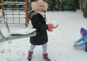 Zimowe zabawy na śniegu, dzieci lepią kule śniegowe