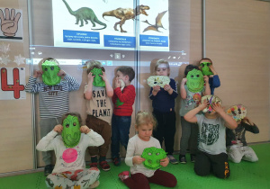 Wspólne pamiątkowe zdjęcie grupowe w maskach dinozaurów.