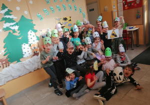 Zdjęcie grupowe dzieci w własnoręcznie wykonanych maskach dinozaurów.