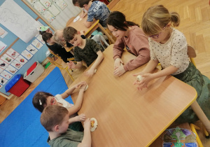 Dzieci odciskają figurkę dinozaura w masie solnej.
