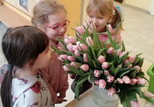 Dziewczynki wąchają tulipany.