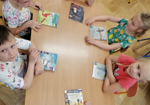 Dzieci oglądają i czytają książki przy stoliku