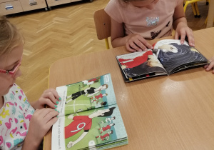 Dzieci oglądają i czytają książki przy stoliku