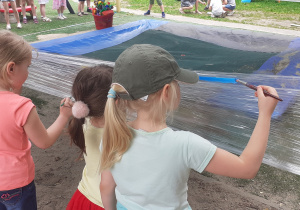 Dzieci malują farbami w plenerze na folii