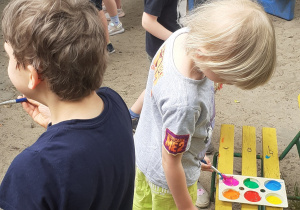 Dzieci malują farbami w plenerze na folii