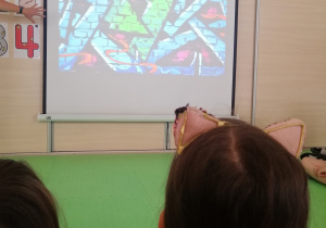 Dzieci słuchają i oglądają prezentacje multimedialną na temat tworzenia graffiti