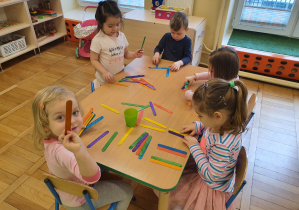 Dzieci przy stoliku układają różne formy z kolorowych patyczków