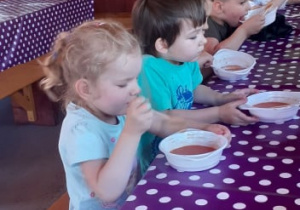 Dzieci przy stoliku jedzą zupę
