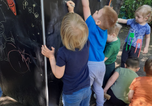 Dzieci rysują kolorową kredą po tablicy