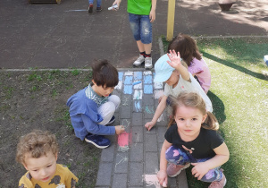 Dzieci rysują kolorową kredą po alejkach