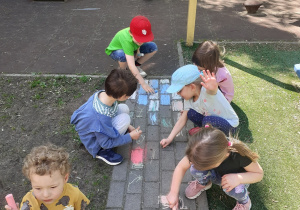 Dzieci rysują kolorową kredą po alejkach