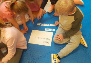 Dzieci w małych zespołach wykonują zadanie przygotowujące do nauki czytania
