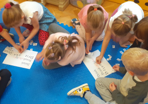 Dzieci w małych zespołach wykonują zadanie przygotowujące do nauki czytania