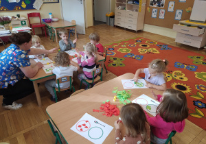 Przedszkolaki ćwiczą rączki poprzez rwanie papieru na małe kawałki.