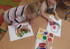 Dzieci malują farbami przy stoliku.