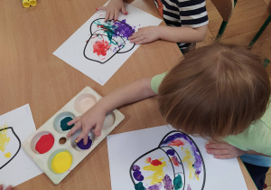 Chłopcy malują farbami za pomocą palców u rąki.
