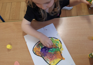 Dziewczynka przykleja kolorowe liście.