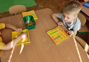 Dzieci naciągają gumki recepturki na kołki tworząc kolorowe wzory