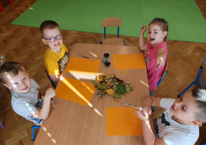 Dzieci wyklejają kropkę jesiennym materiałem przyrodniczym