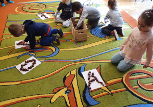 Dzieci układają z kasztanów kształty liter