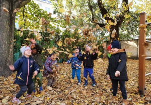 Dzieci z radością podrzucają w górę jesienne liście