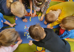 Dzieci bawią się kolorowymi guzikami układając z nich wzory