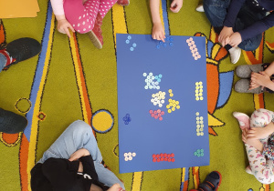 Dzieci segregują guziki wg kolorów i układają z nich zbiory. Przeliczają elementy.