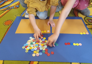 Dzieci z kolorowych guzików układają wzory