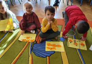 Dzieci prezentują swoje prace plastyczne z małymi dyniami i opowiadają co na nich widać