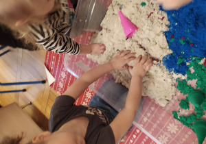 Dzieci ugniatają piasek kinetyczny.