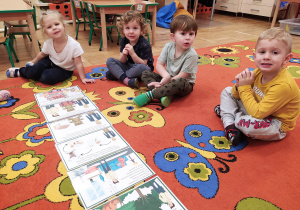 Dzieci siedzą na dywanie i oglądanie ilustracje.