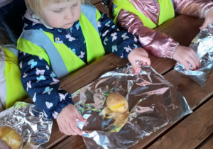 Dzieci zawijają w folię ziemniaki do pieczenia