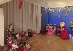 Zdjęcie przedszkolaków z Mikołajem w tle.
