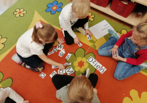 Dzieci na dywanie układają wyrazy z liter