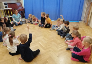Dzieci siedzą w kole na podłodze i słuchają opowiadania Pani Weterynarz