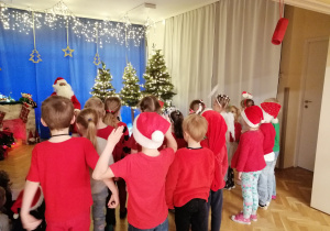 Dzieci stoją i prezentują Mikołajowi przygotowaną piosenkę.