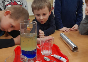 Dzieci obserwują reakcje chemiczne w pojemniku z olejem, sodą i wodą