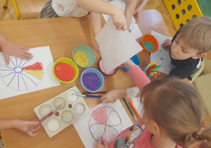 Dzieci przygotowują kolorowe mandale z wykorzystaniem barwionego