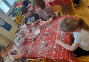 Dzieci przy stoliku lepią z gliny