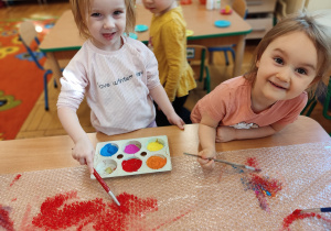 Dziewczynki malują farbami.