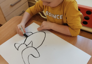 Chłopiec maluje węglem.