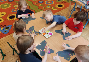 Dzieci wykonują motyla z wykorzystaniem farb.