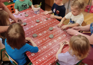 Dzieci bawią się gliną przy stoliku.