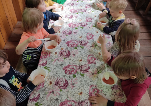 Dzieci jedzą zupę.