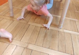Dziewczynka ciąga się pod stolikiem.