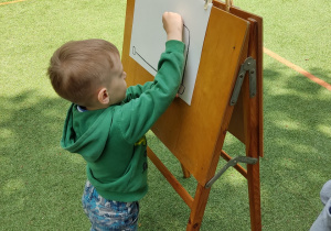 Chłopiec maluje na sztaludze.