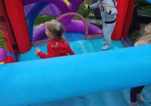 Dzieci skaczą na dmuchanym zamku.