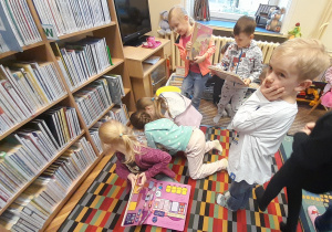 Dzieci wybierają i oglądają książki znajdujące się w bibliotece